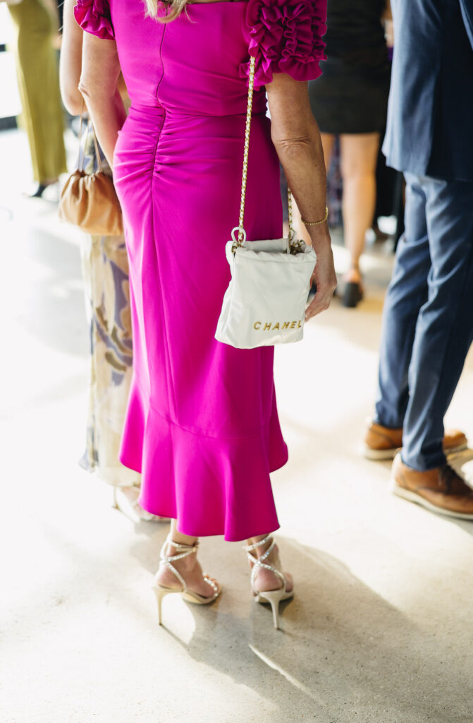 woman in a bright pink dress with a white chanel bag draped over her shoulder