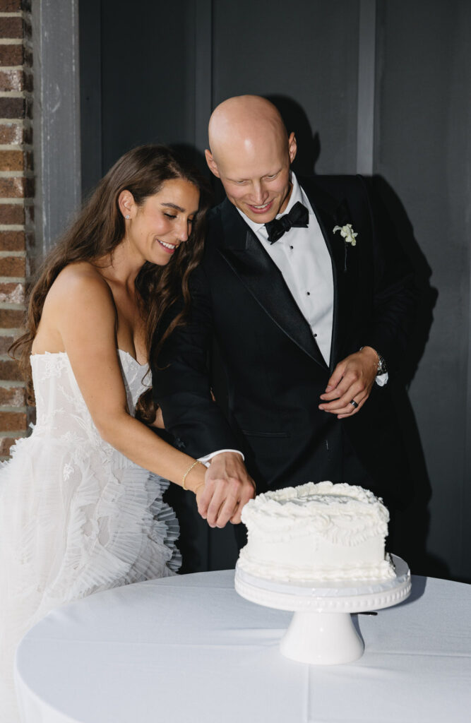 bride and groom cutting into a small white cake from Sweet Bree's Bakeshop in Detroit Michigan