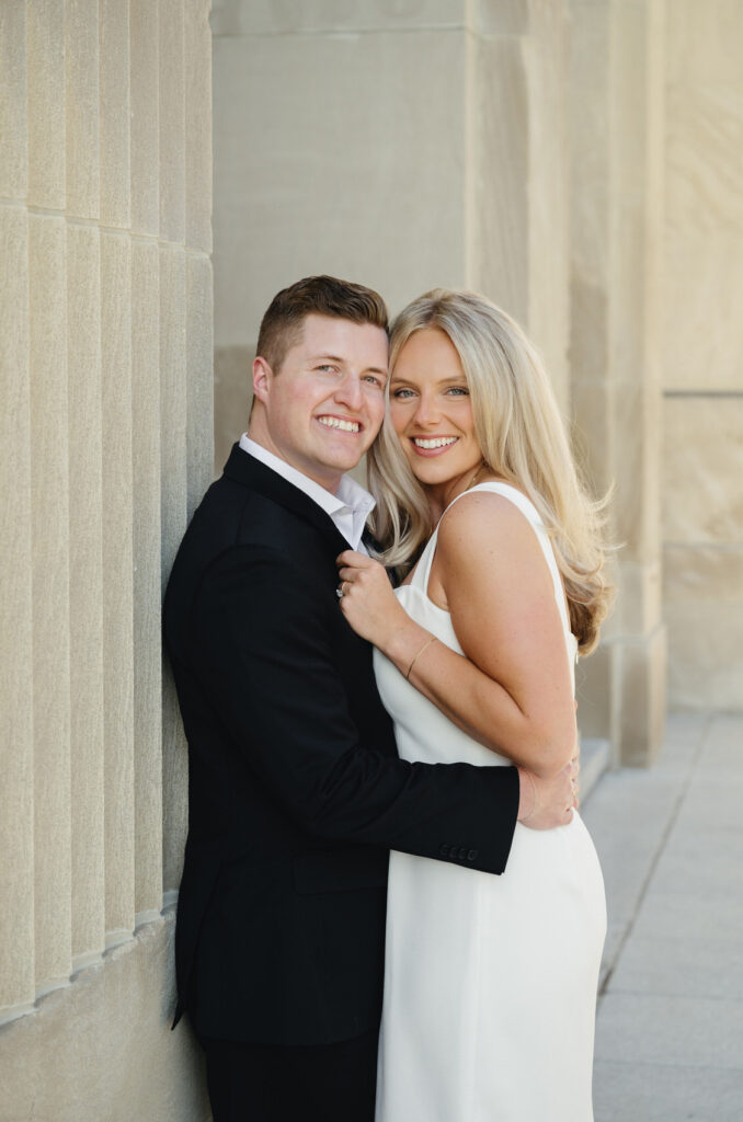 engaged man in a black suite holding his fiance in a white dress in front of the Civic Auditorium in downtown Grand Rapids