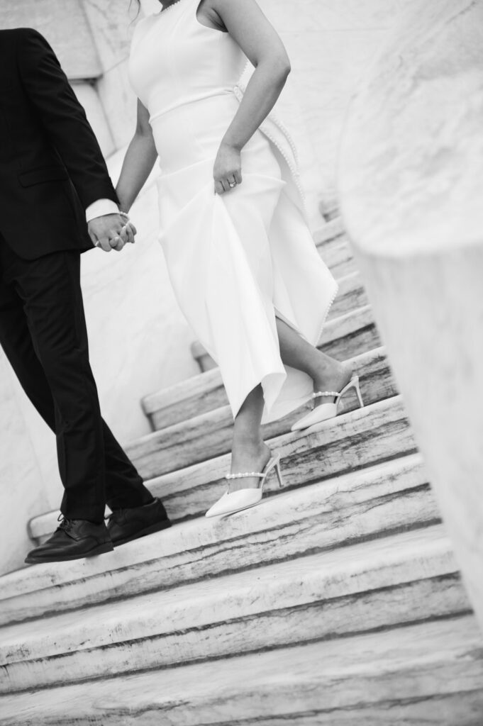man leads his fiance hand in hand down the white marble staircase of the Detroit Institute of Arts