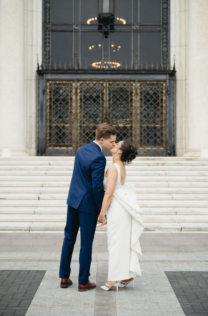 engaged couple holding hands and kissing in front of the Detroit Institute of Arts