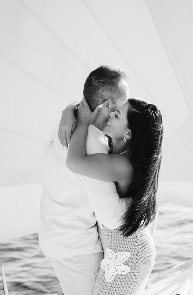 woman in a crochet dress hugs her fiance on a sailboat on Lake Michigan