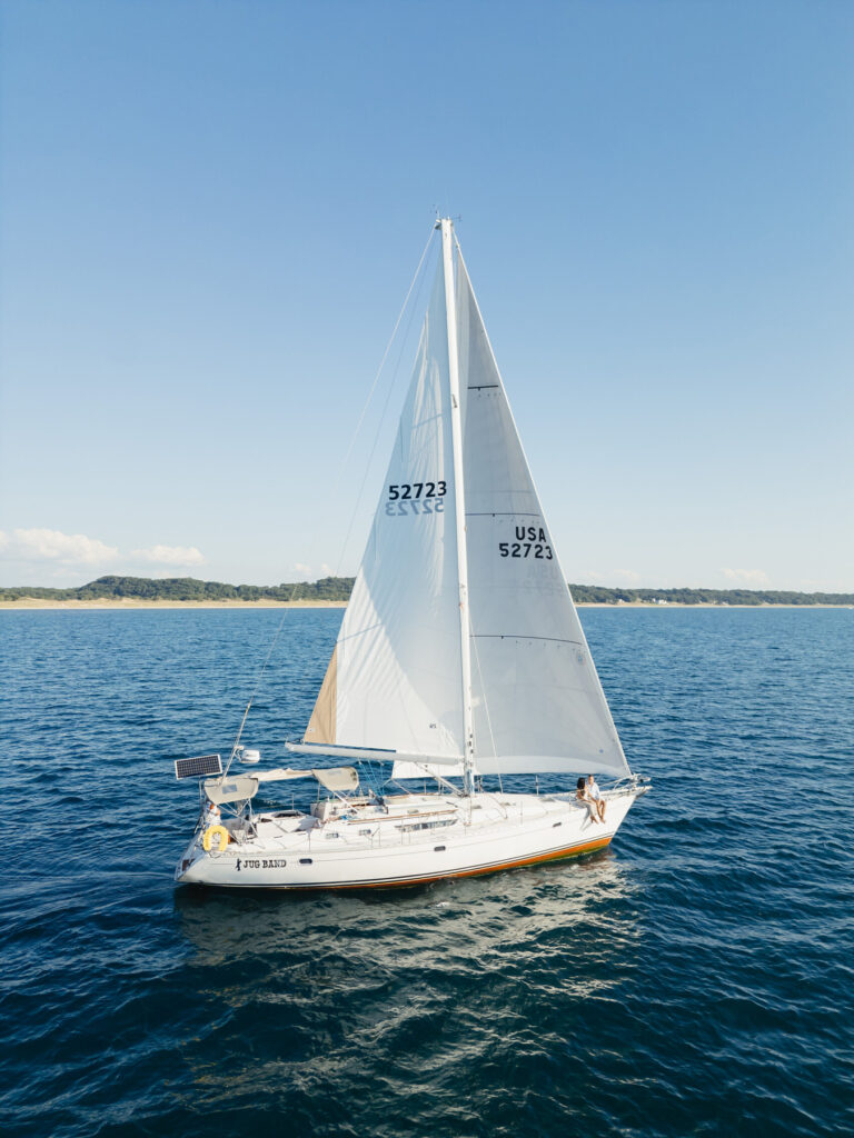 a white sailboat sailing on Lake Michigan with clear blue skies and blue water