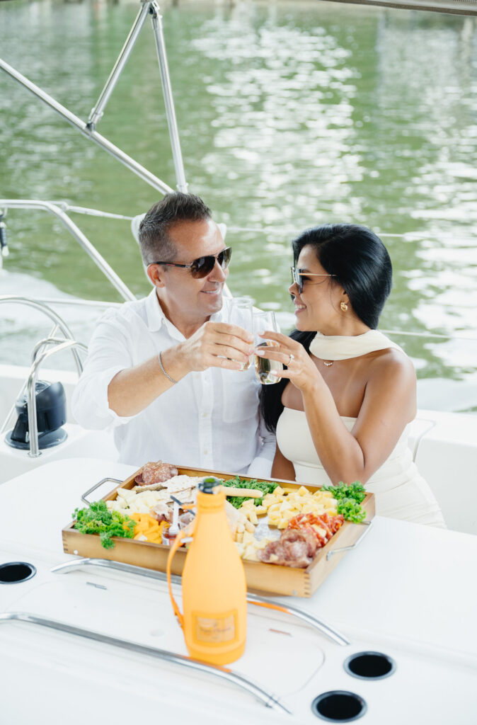 man and woman cheers their champagne glasses on a boat cruise