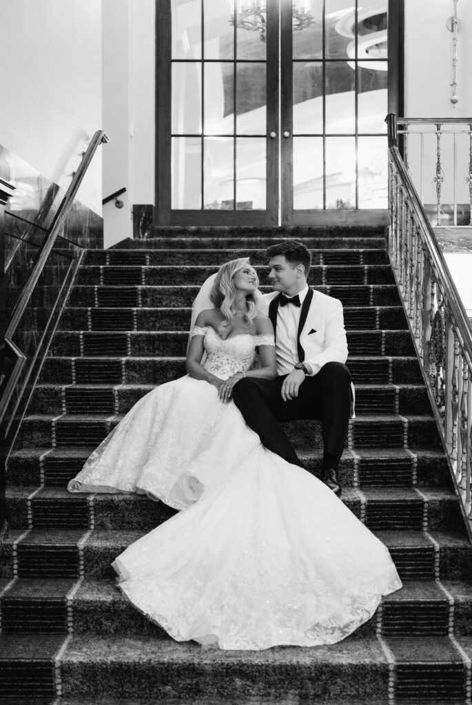 bride and groom sitting together on the stairs of the lobby in the Amway Grand Plaza Hotel in Grand Rapids