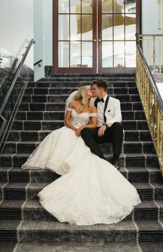 bride and groom sitting on the stairs and kissing in the lobby of the Amway Grand Plaza Hotel